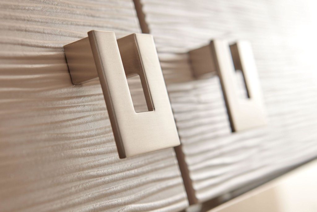 A modern type of metal knobs attached to light wood kitchen cabinets.