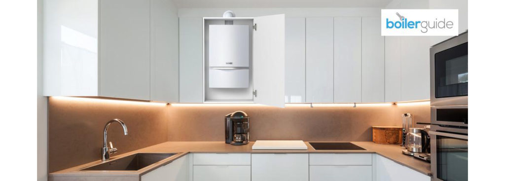 A compact boiler placed in a white kitchen cupboard.