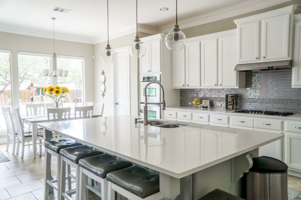 A beautiful white kitchen. White cabinets, white counters, white tables and chairs, etc.