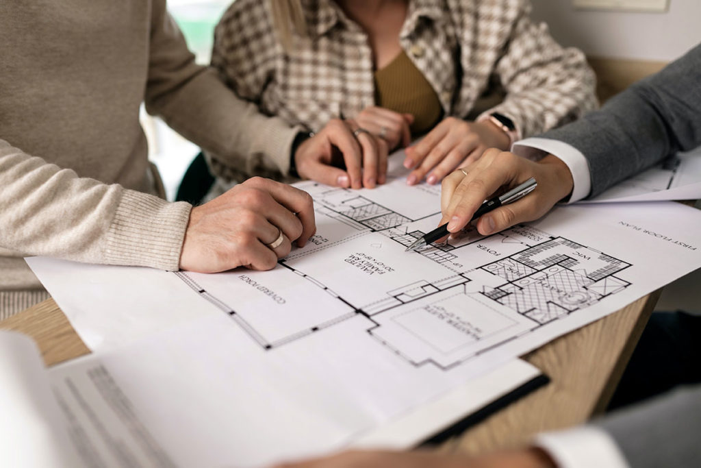 Man showing a house plan to a couple